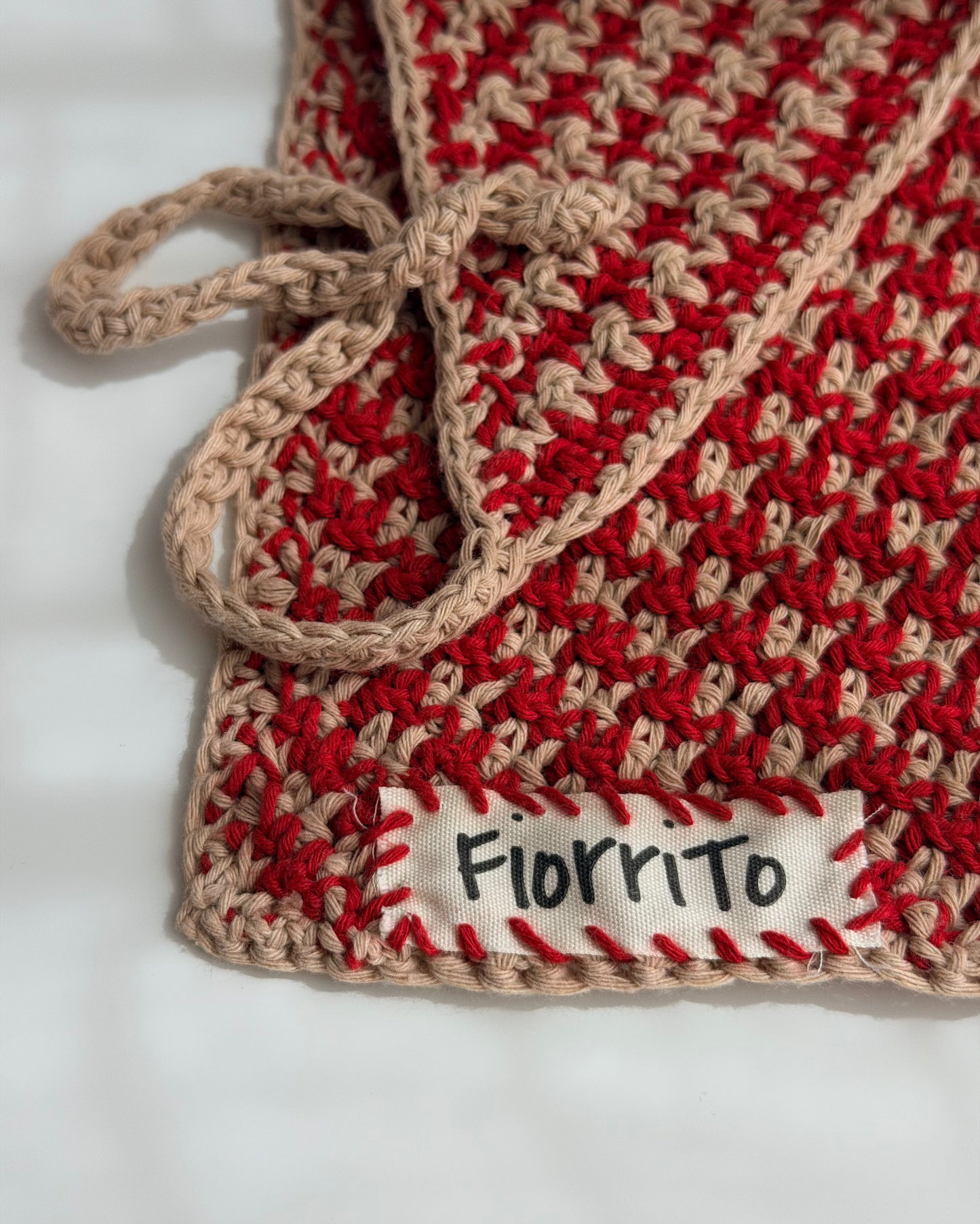 Red and beige crocheted blanket with 'Fiorrito' label on a white background