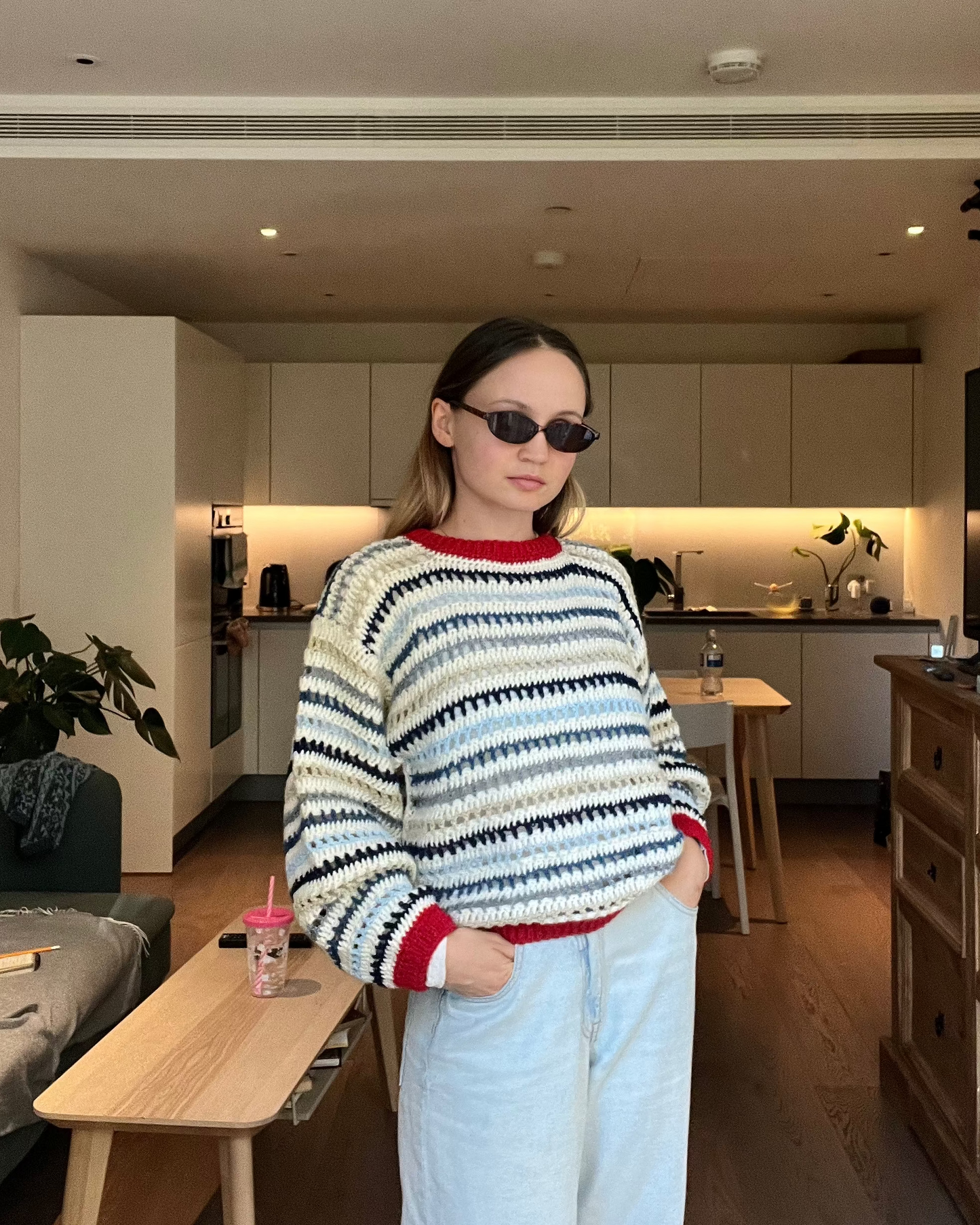 Person wearing a colorful sweater and sunglasses in a modern kitchen.