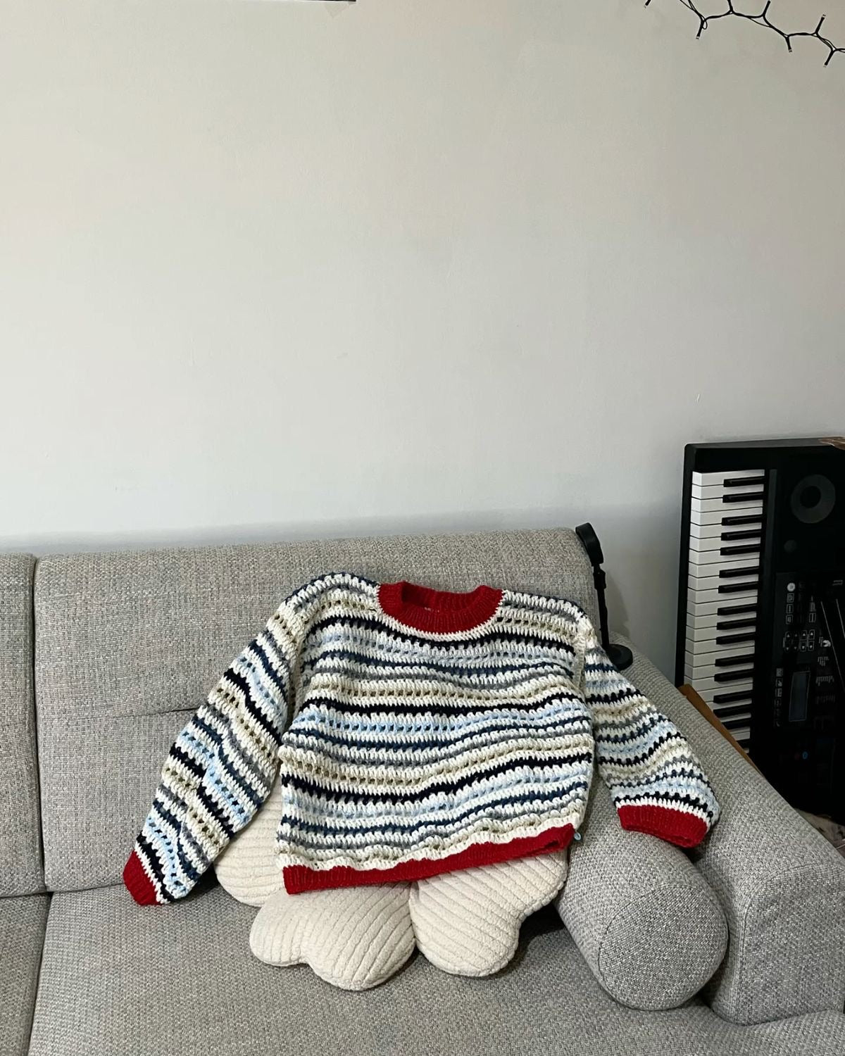 Striped sweater with red accents on a gray couch against a white wall.