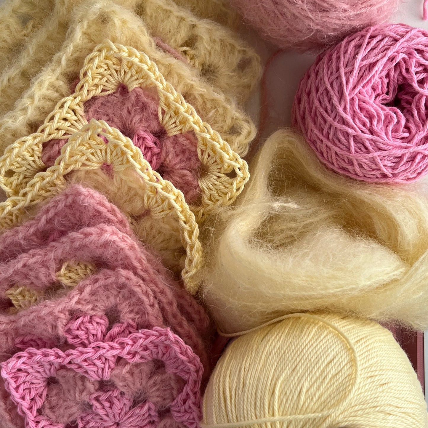 Close-up of pink and beige yarn with crochet patterns and loose yarn strands.