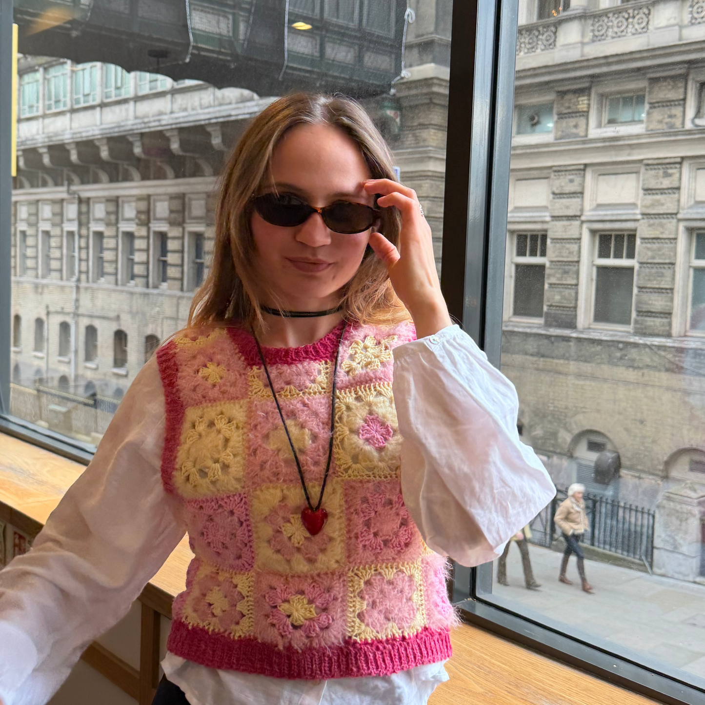 Person wearing a colorful knitted sweater with a cityscape in the background