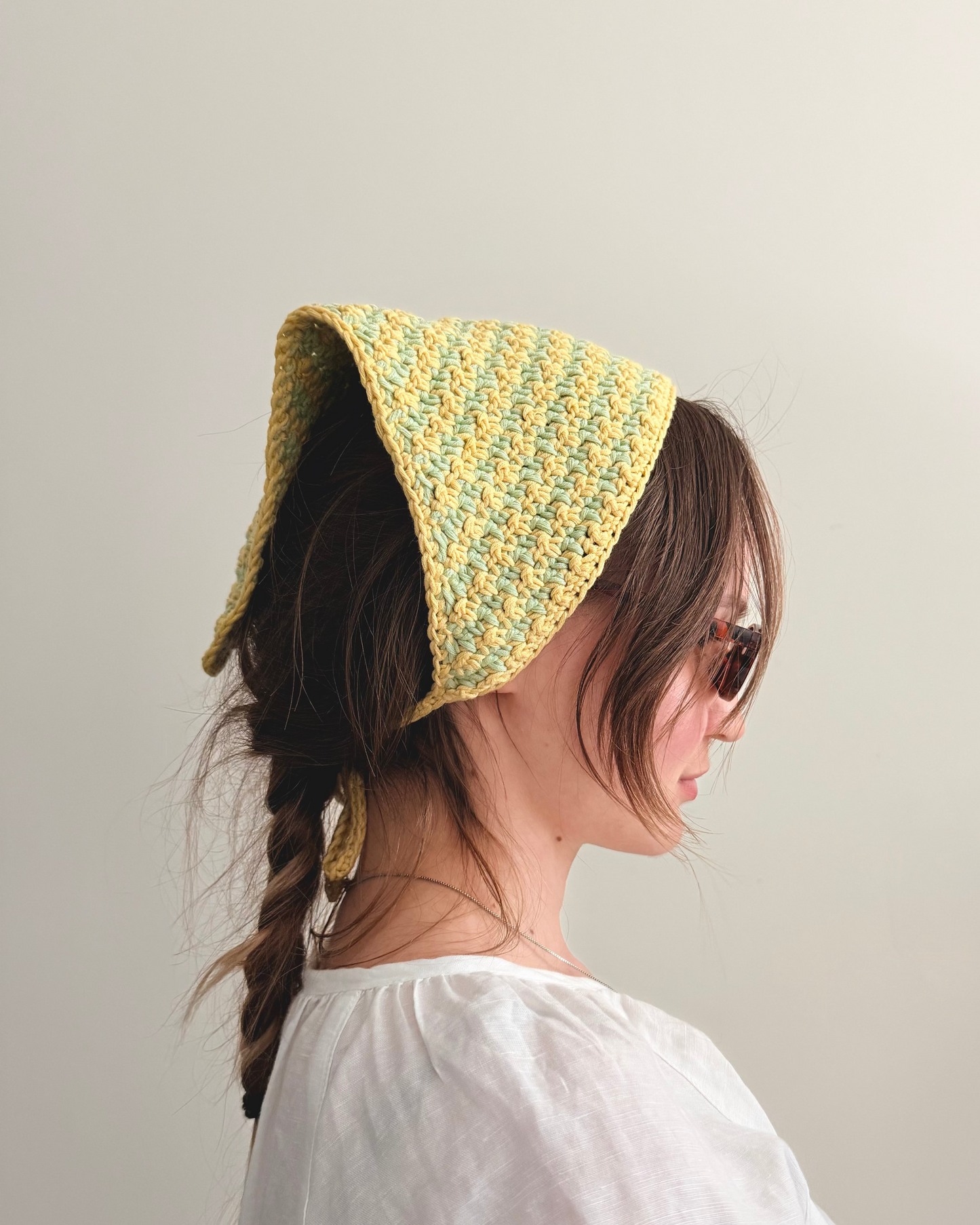 Person wearing a yellow knitted bonnet against a plain background