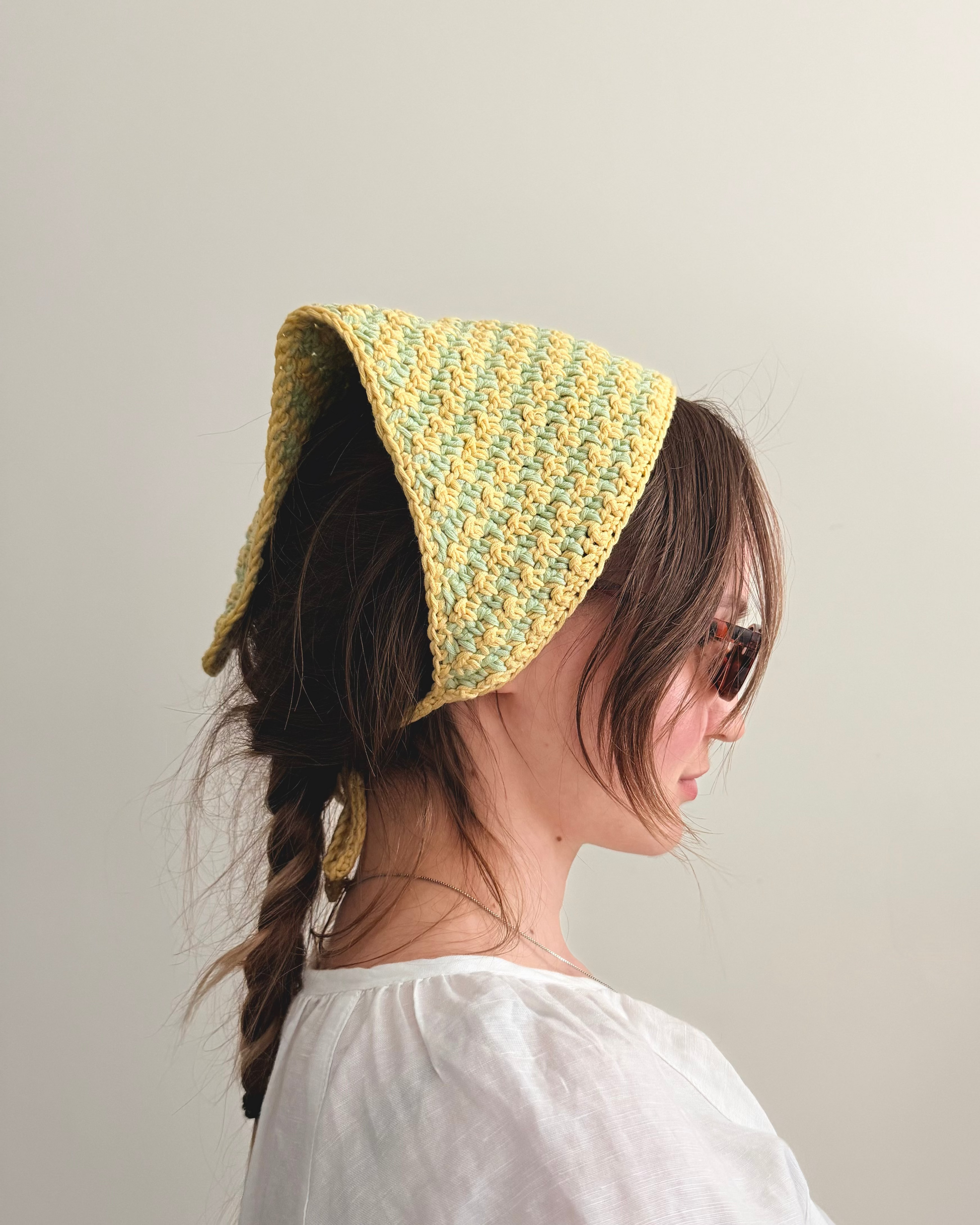 Person wearing a yellow knitted bonnet against a plain background